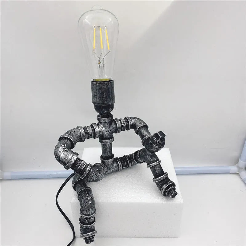 Industrial vintage table lamp shaped like a robot made from iron water pipes in a retro colour.