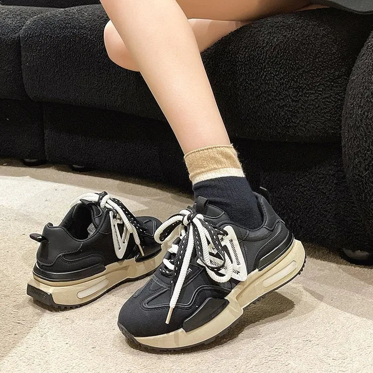Women's black platform trainers with round toe and lace-up design, showing rubber sole