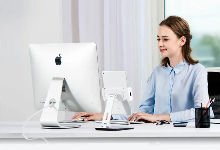 Folding aluminium desktop phone and tablet stand with 360-degree rotation on a wooden desk.