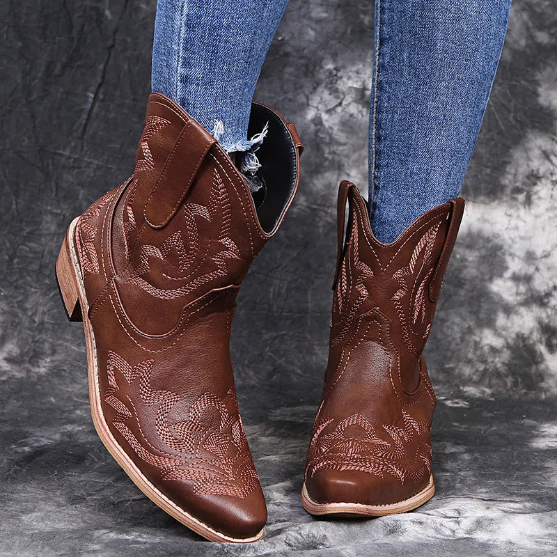 Blue women's cowboy boots with embroidery and a low wedge heel on a wooden floor.