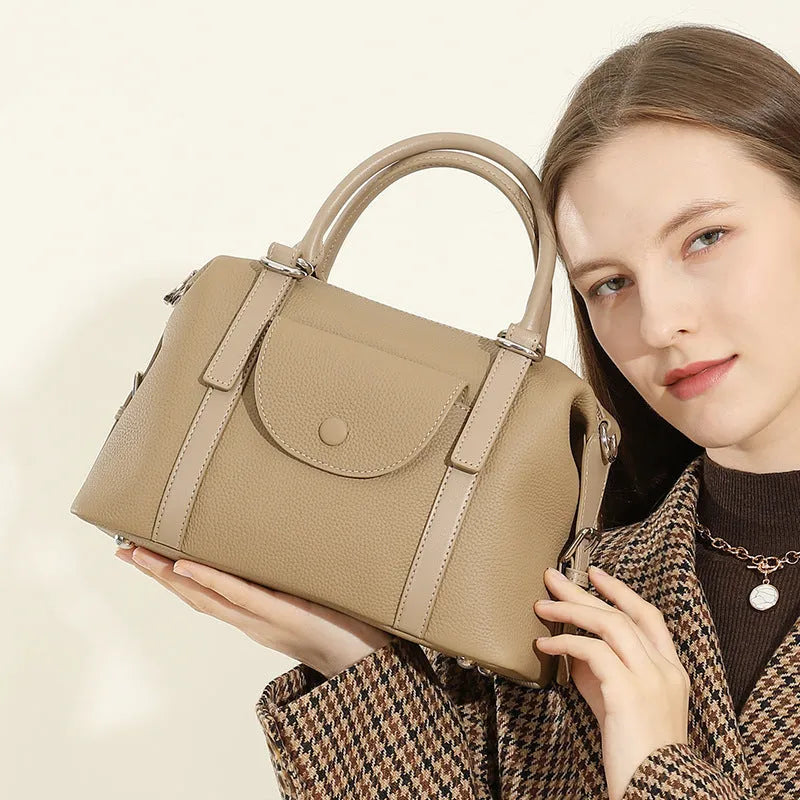 Black genuine leather ladies handbag with single shoulder strap, showing contrast lock and stitching.