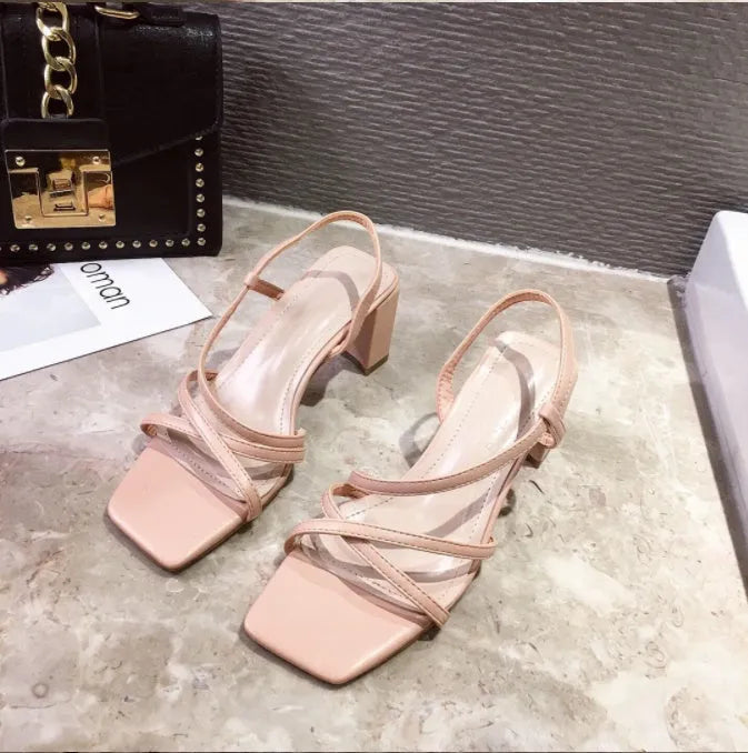 Women's white thick heel roman sandals with overshoot design on a flat background.