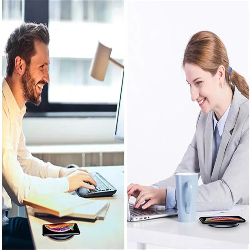 Black 15W fast wireless charging pad on a wooden desk next to a smartphone.
