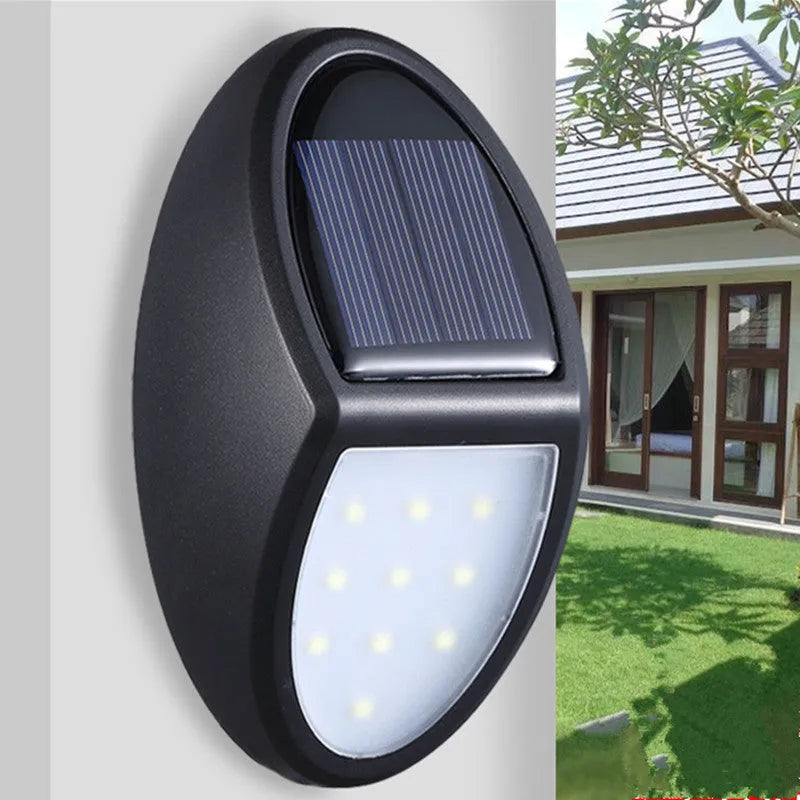 Black rectangular LED solar-powered outdoor wall light mounted on a fence.