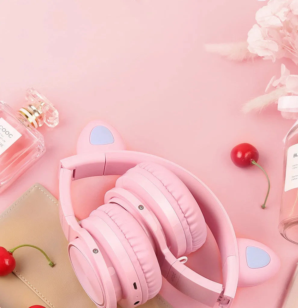Pink white Luminous over-ear Bluetooth headset with braided wire and large ear cushions.
