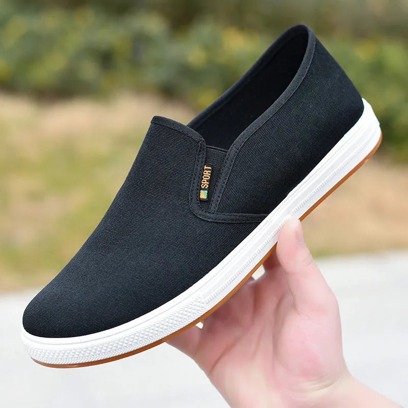 Men's low-top slip-on canvas shoe in blue on a white background, showing round toe and shallow mouth design.