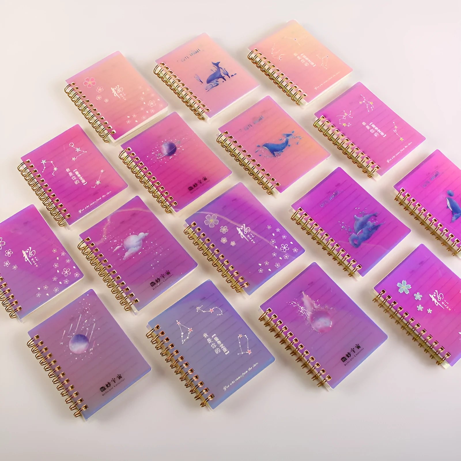 Set of four A7 spiral-bound pocket notebooks with different coloured PP covers showing Constellation, Sakura, Ocean, and Universe designs.