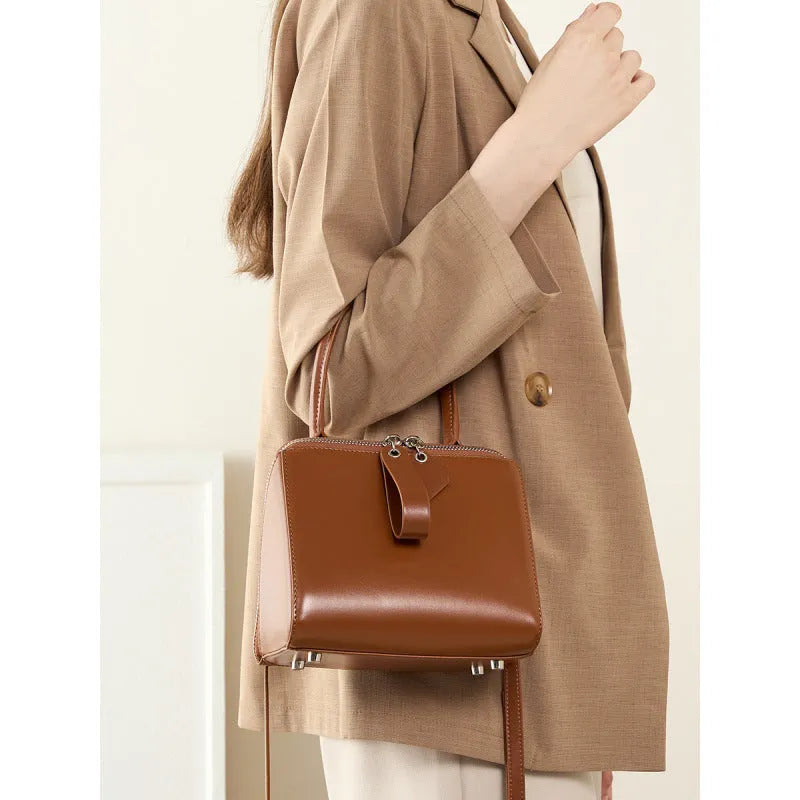 Open grain leather handbag in black with visible grain texture and welt pocket on front