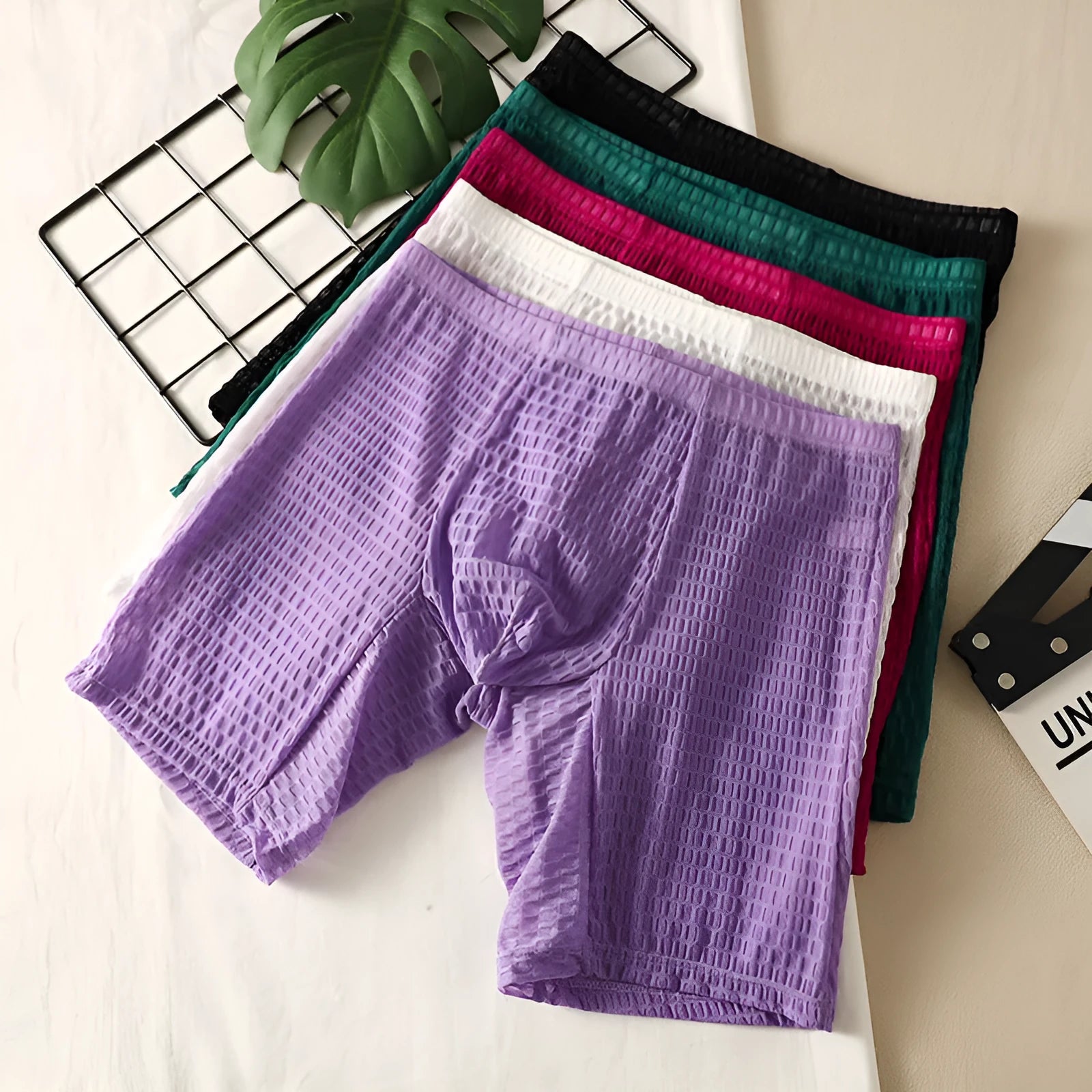 Men's solid colour lace boxer shorts on a white background, showing the textured fabric and hip-lifting shape.