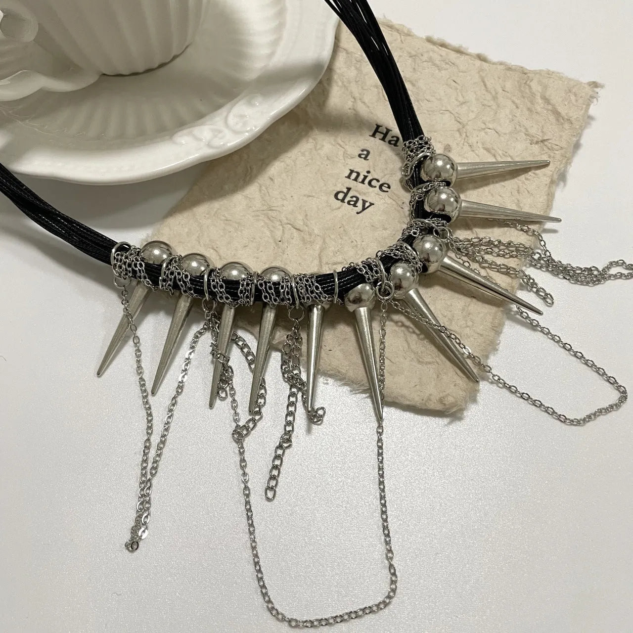 Women's casual leather necklace with a winding tassel, round beads, and silver rivet details.