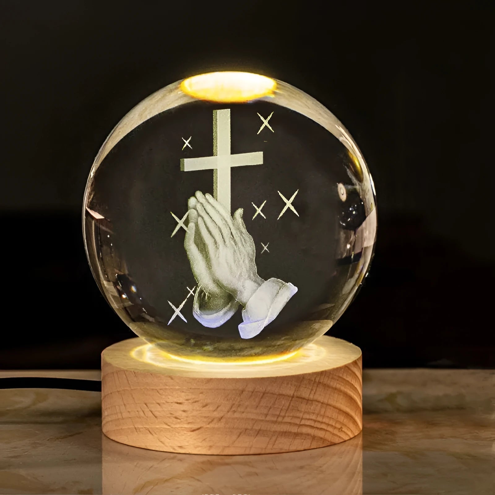 White crystal ball ornament on wood base with warm light and religious symbols
