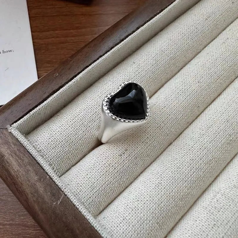 S925 sterling silver adjustable ring with a black agate heart design on a finger.
