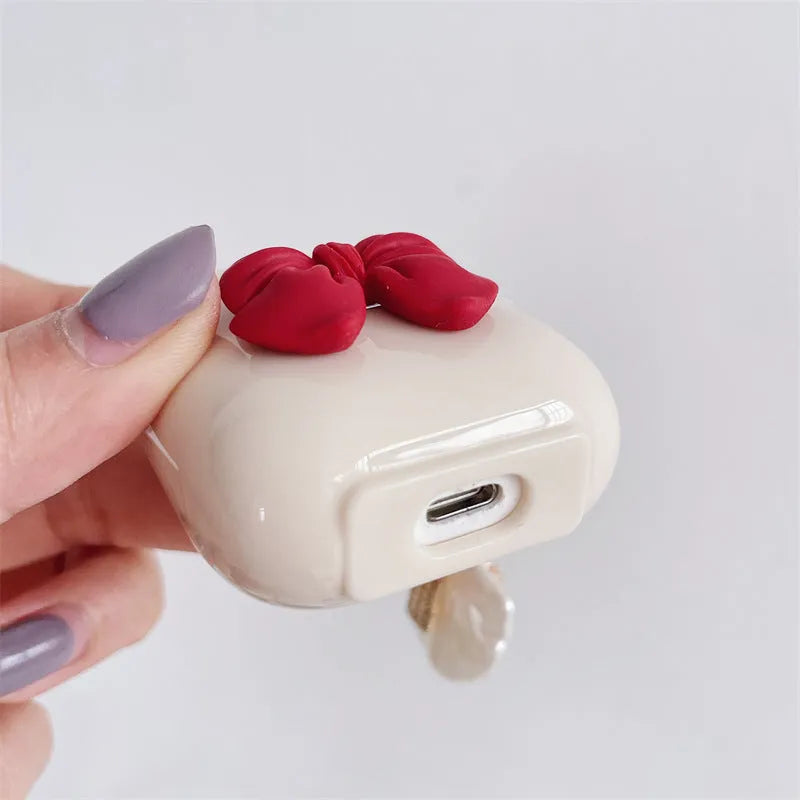 Beige AirPods case with red bow shell design, clamshell TPU earphone cover