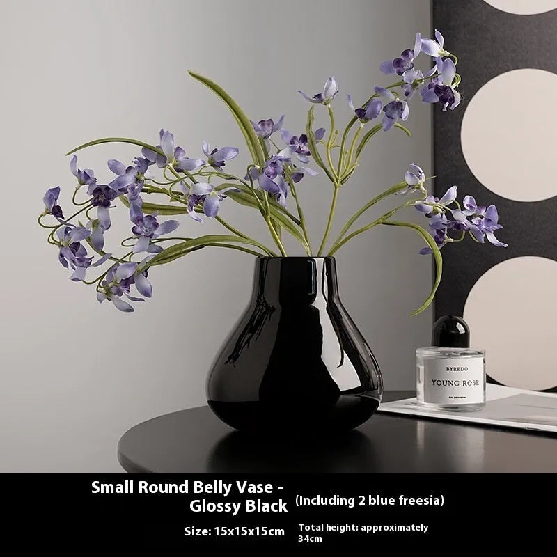 Ceramic decorative vase with coloured glaze surface and artificial orchid flowers in black or white colour