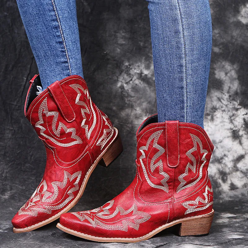 Blue women's cowboy boots with embroidery and a low wedge heel on a wooden floor.