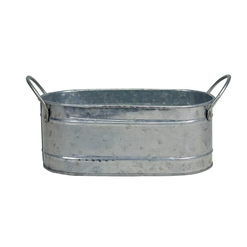 Galvanised iron cylindrical succulent flower pot with a drainage hole on a desk.