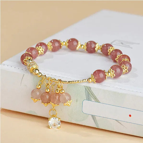 Pink women's bracelet with heart-shaped strawberry quartz crystal beads and freshwater pearl accents on a wrist.