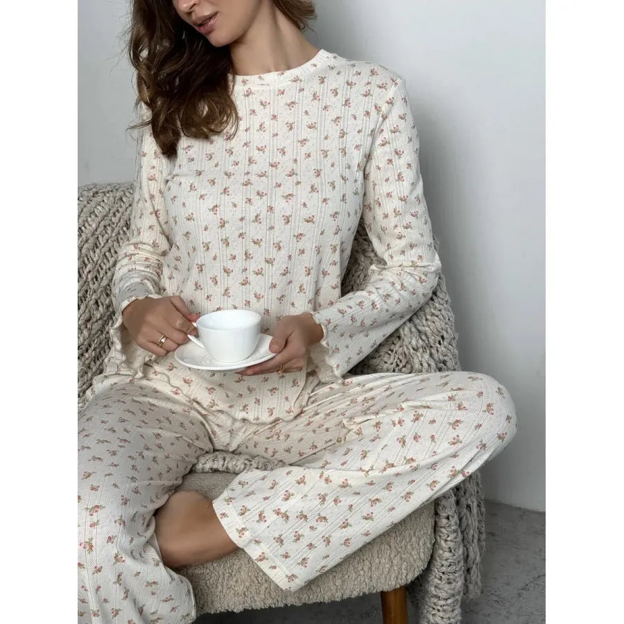 Women's white floral print suit set featuring a round neck top with bell sleeves and wide leg trousers.
