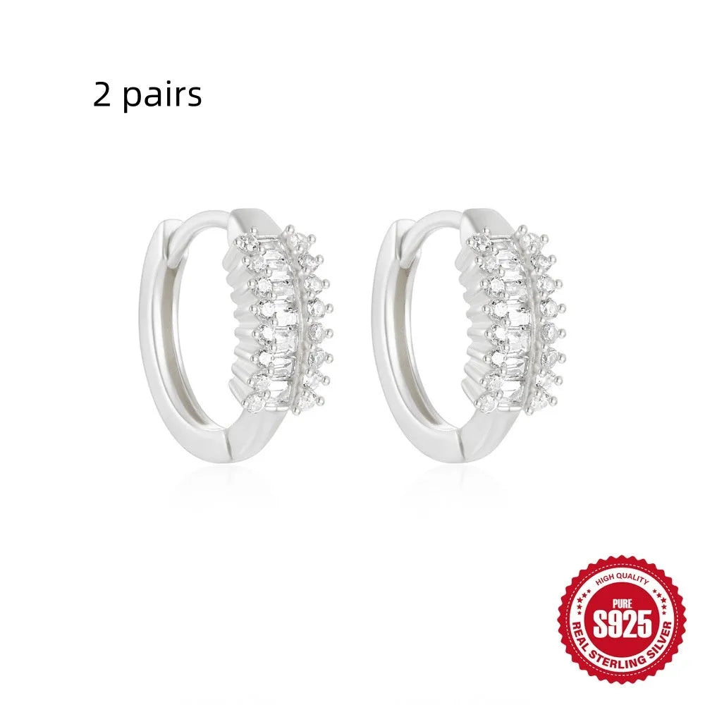 A pair of small, round, geometric stud earrings made of sterling silver with an electroplated finish.