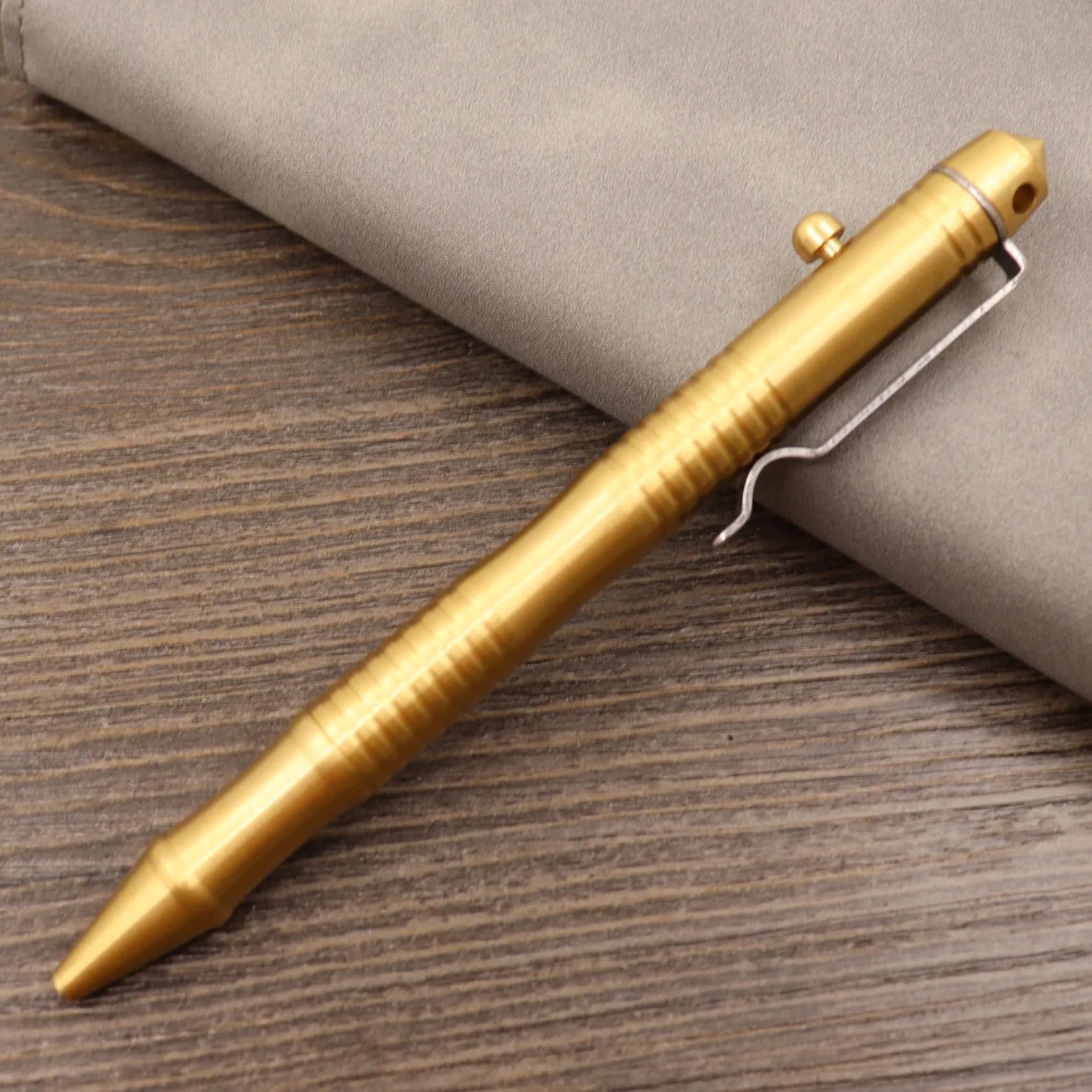 Retro brass tactical pen with cylindrical barrel and six-ring grip, shown with press mechanism extended