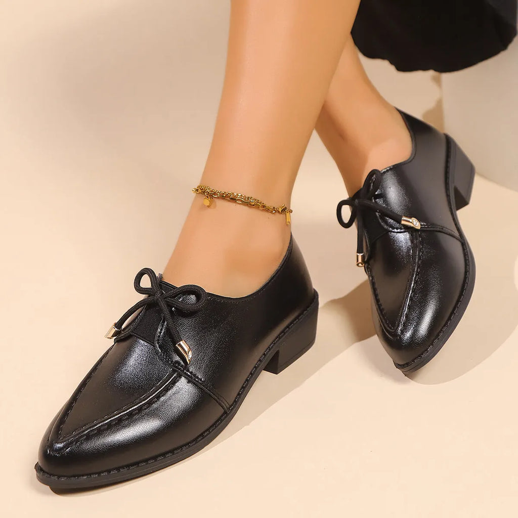 Women's British-style leather-look shoes with decorative bow detail on pointed toe