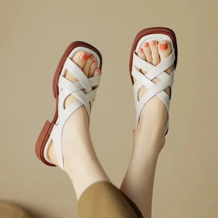 Glossy black patent leather women's sandals with a cross-band design, square toe, and low rubber sole.