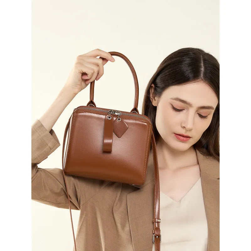 Open grain leather handbag in black with visible grain texture and welt pocket on front