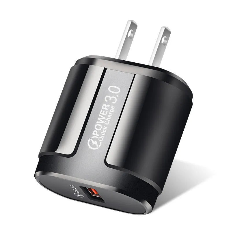 White and black mobile phone travel chargers with UK, US, and EU plug attachments on a table