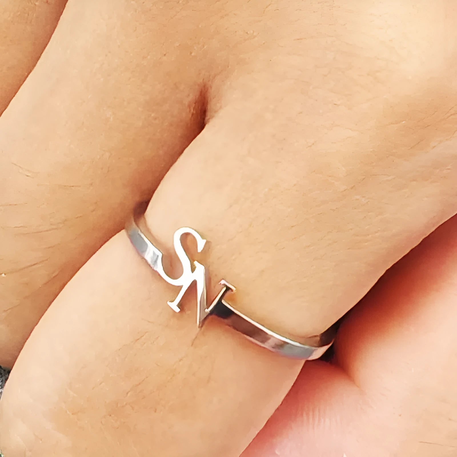Customised two-letter open ring in stainless steel silver and gold electroplated finish on a white background