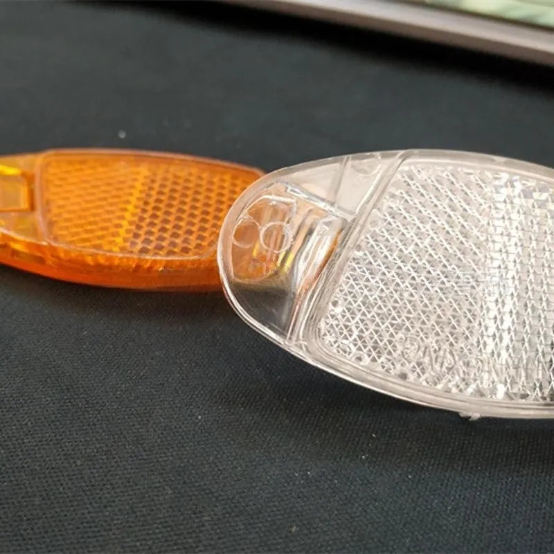 Bicycle spoke reflector showing yellow plastic construction with clip-on attachment for wheel safety