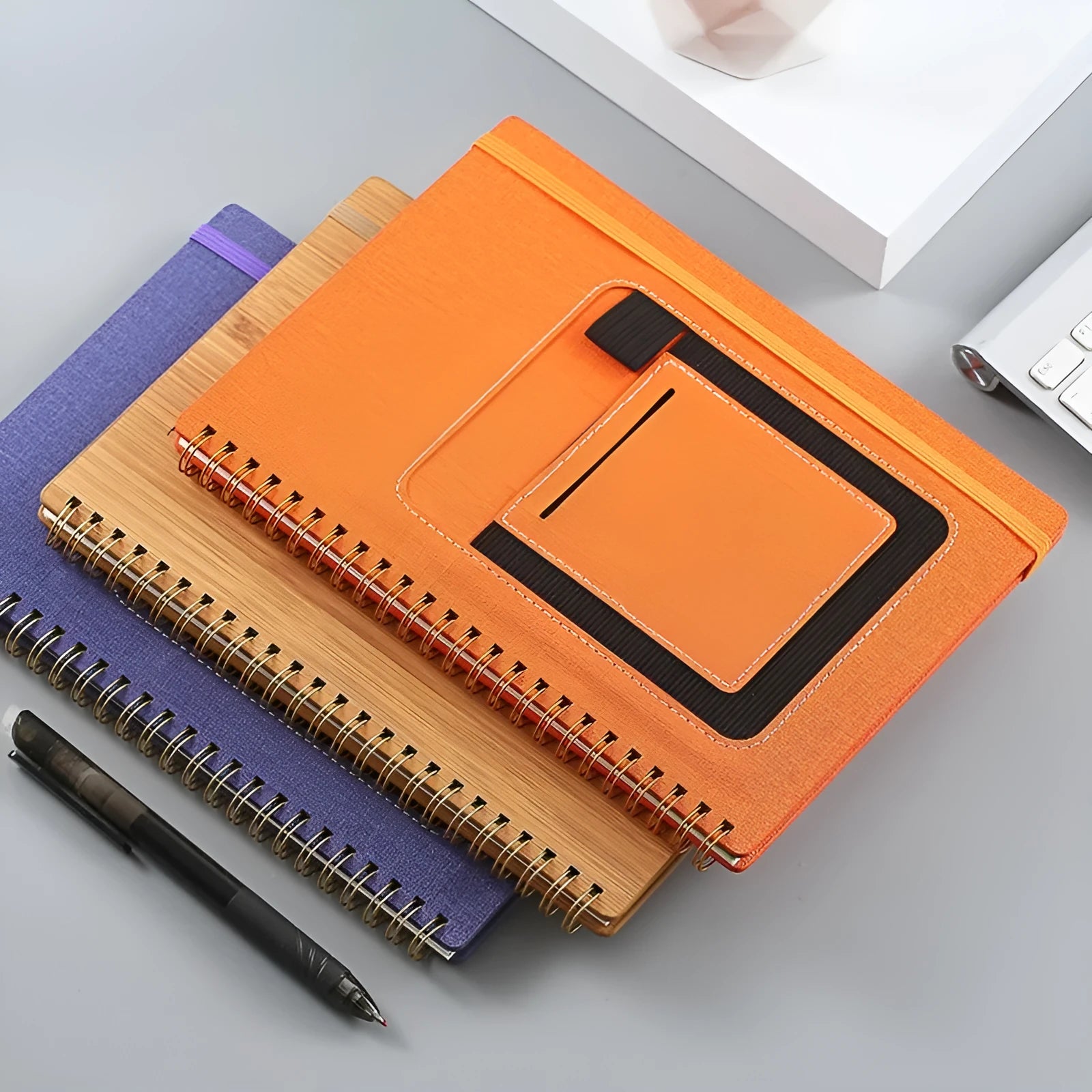 Reusable erasable coil notebook with stone paper, shown with a pen and available in multiple cover colour options.