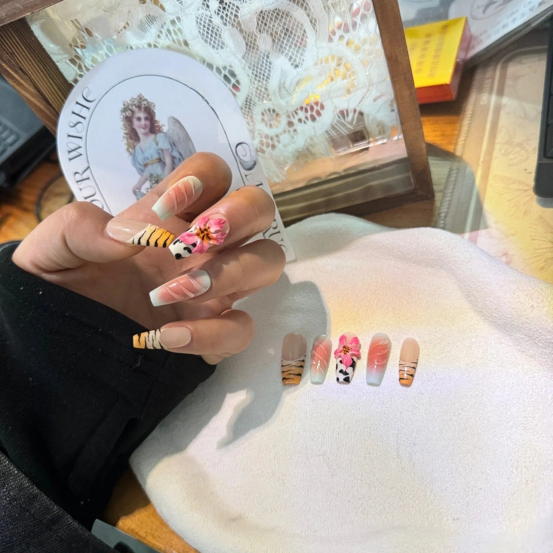 Close-up of hand-carved acrylic press-on nails with a Lily zebra pattern, floral, and leopard print design.