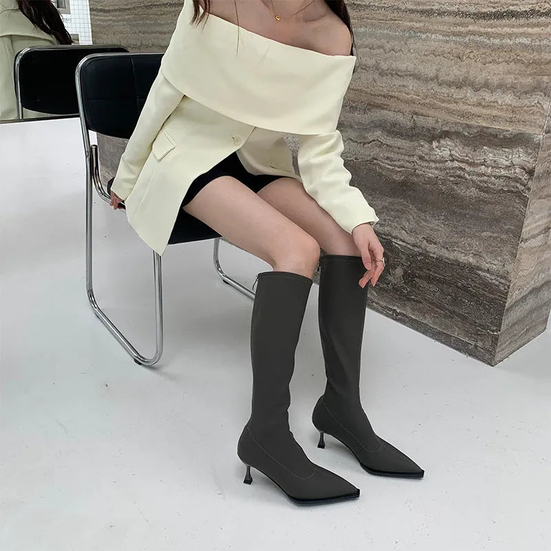 Women's black pointed toe stiletto heel boots with a back zipper, shown below the knee.