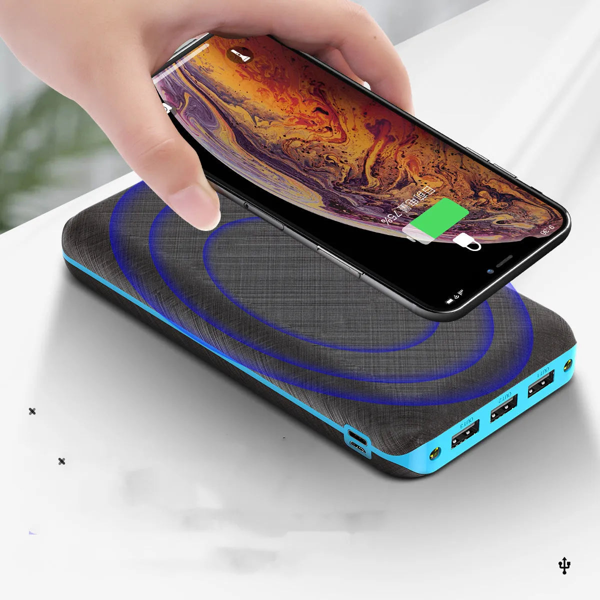 Portable power bank with wireless charging pad and three USB ports in black plastic casing