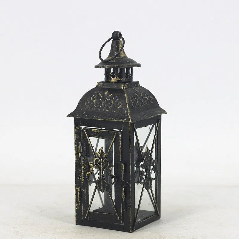 Black wrought iron floor lantern with glass panels on a stone patio.