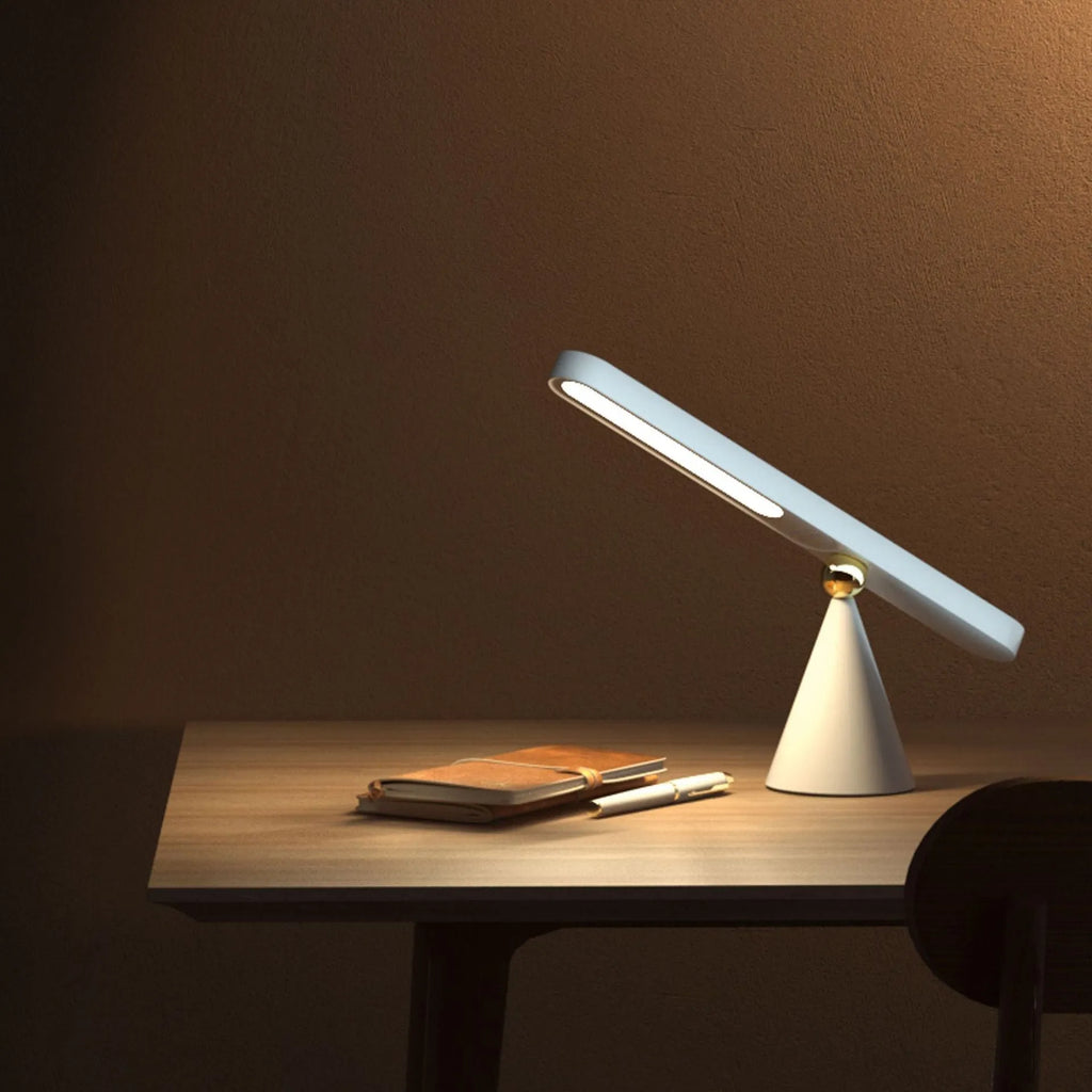 White geometric table lamp with touch switch and USB cable on a wooden desk.
