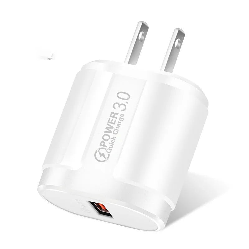 White and black mobile phone travel chargers with UK, US, and EU plug attachments on a table