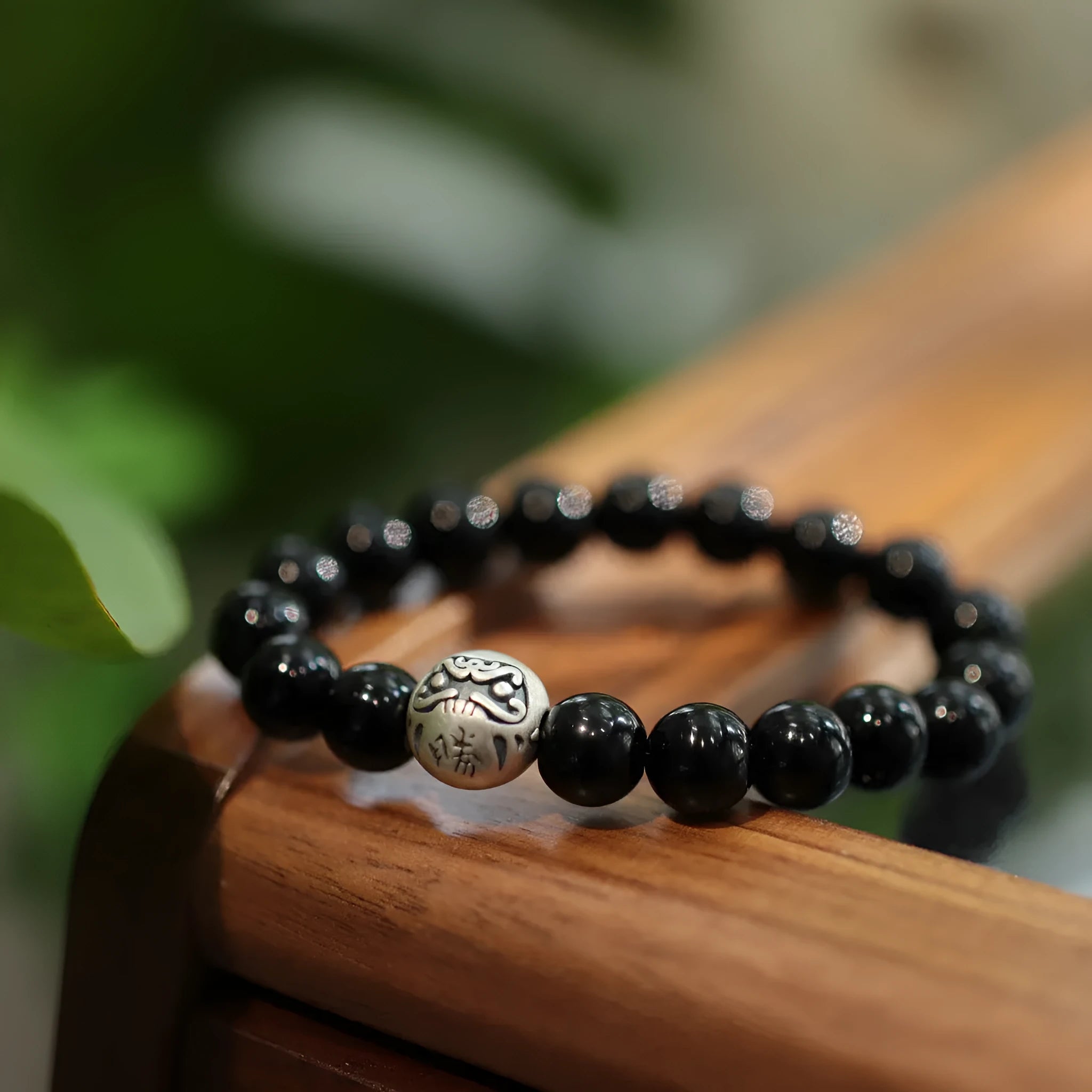 Close-up of a women's bracelet with spherical black agate beads and a shiny sterling silver clasp on a wrist.