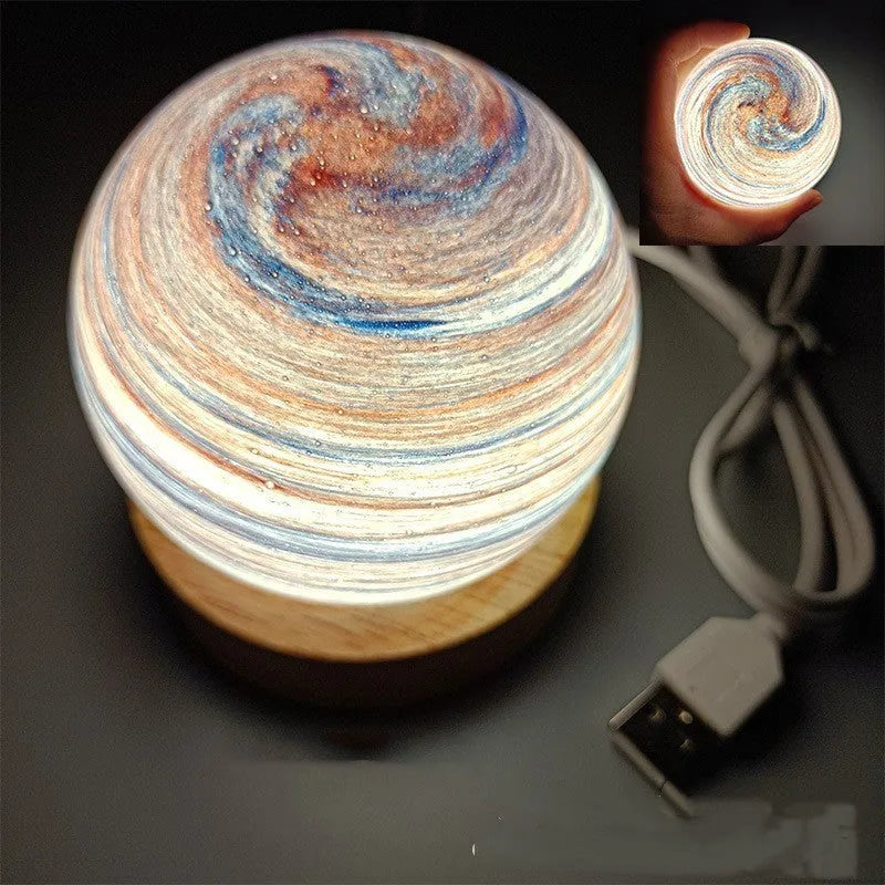 Planet night light with spherical design on base, USB cable connected, showing adjustable three-colour lighting