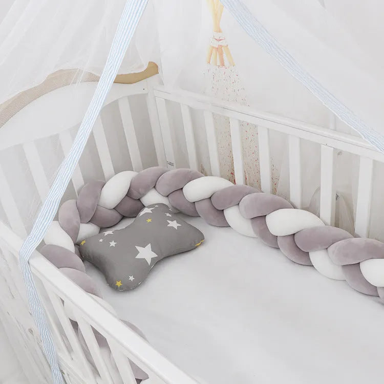 Braided knot baby crib bumper in spandex velvet wrapped around white cot rails.