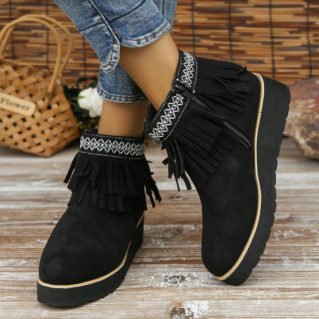 Women's black suede wedge ankle boot with side zip and tassel detail on a thick rubber platform sole.