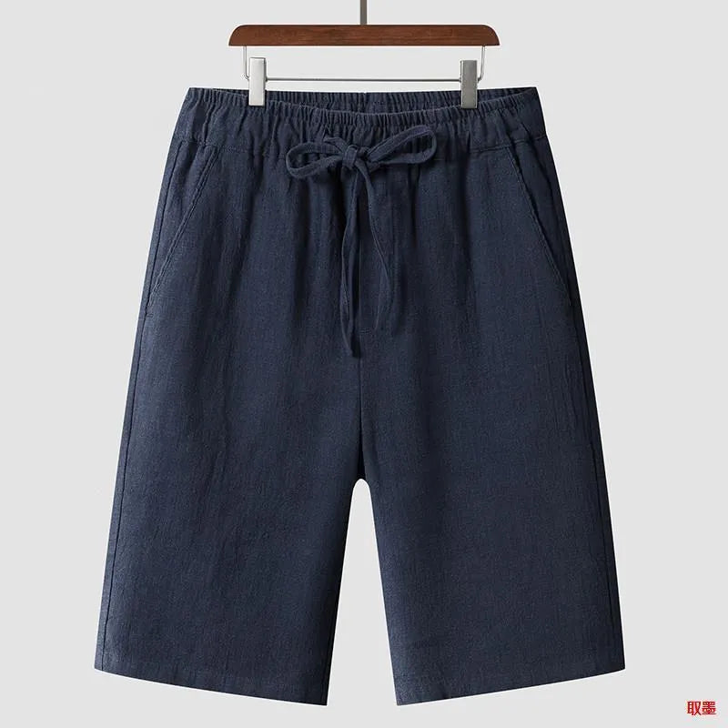 Men's beige linen casual shorts with a loose fit and cropped length on a plain background.