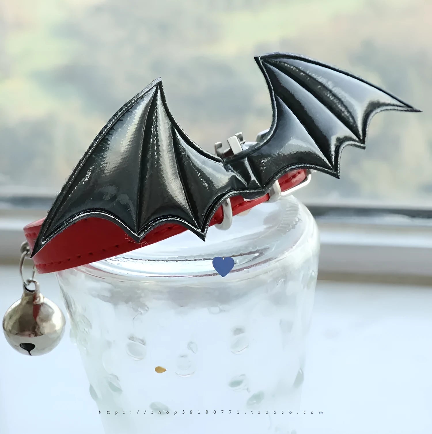 Small black patent leather dog collar with little devil wings charm and bell attached.