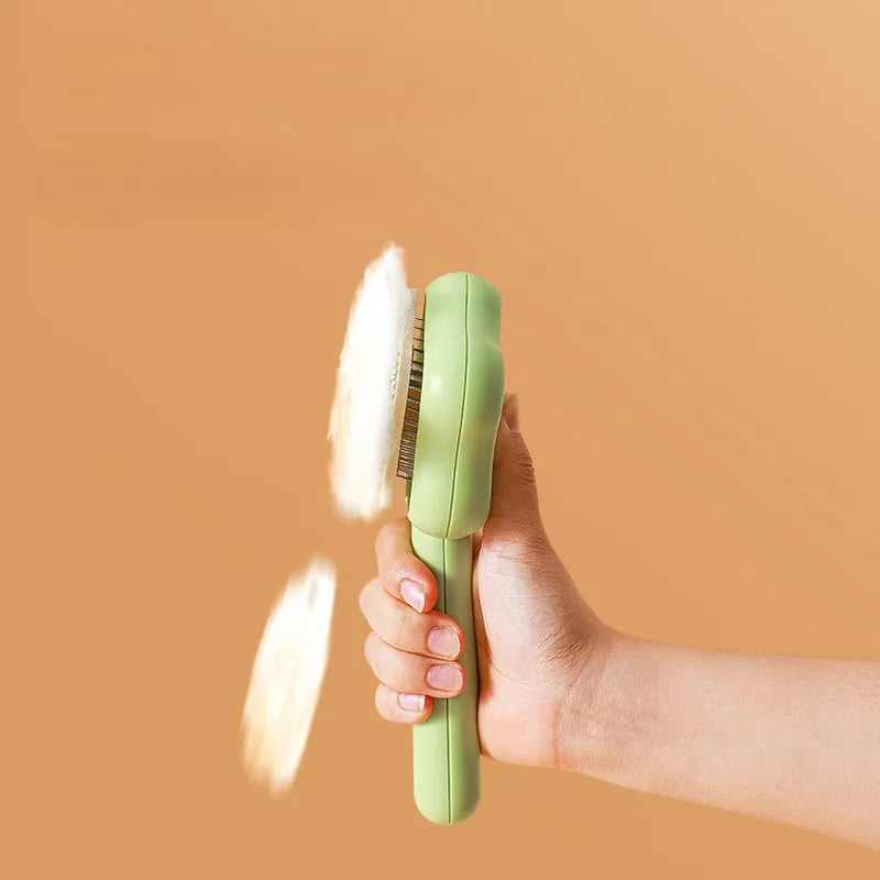 Green and yellow self-cleaning cat grooming comb with stainless steel needles on a white background.