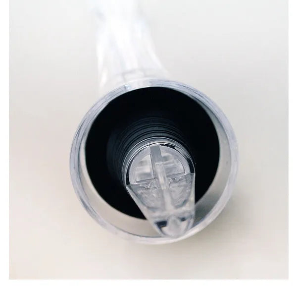A slender, clear acrylic wine aerator pourer with a stainless steel filter inside, shown next to a wine glass.