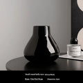 Ceramic decorative vase with coloured glaze surface and artificial orchid flowers in black or white colour
