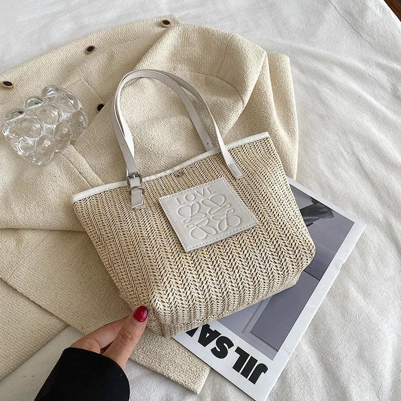Women's straw woven shoulder bag with PU trim showing tapered shape and sewn thread details