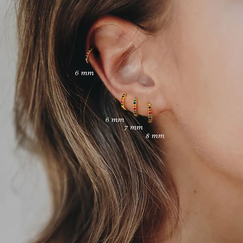Set of gold, rose gold, and silver perforated circle stud earrings in multiple sizes on a flat surface.