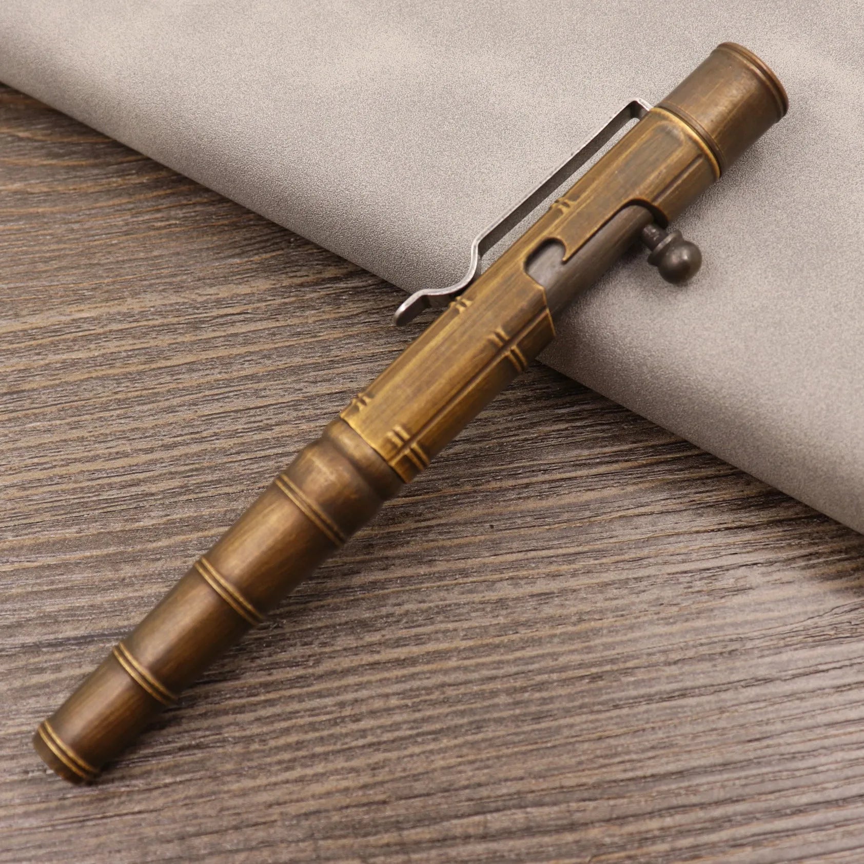 Retro brass tactical pen with cylindrical barrel and six-ring grip, shown with press mechanism extended