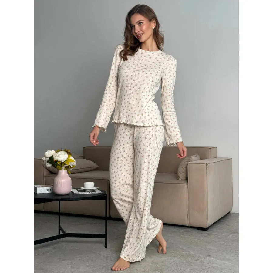 Women's white floral print suit set featuring a round neck top with bell sleeves and wide leg trousers.